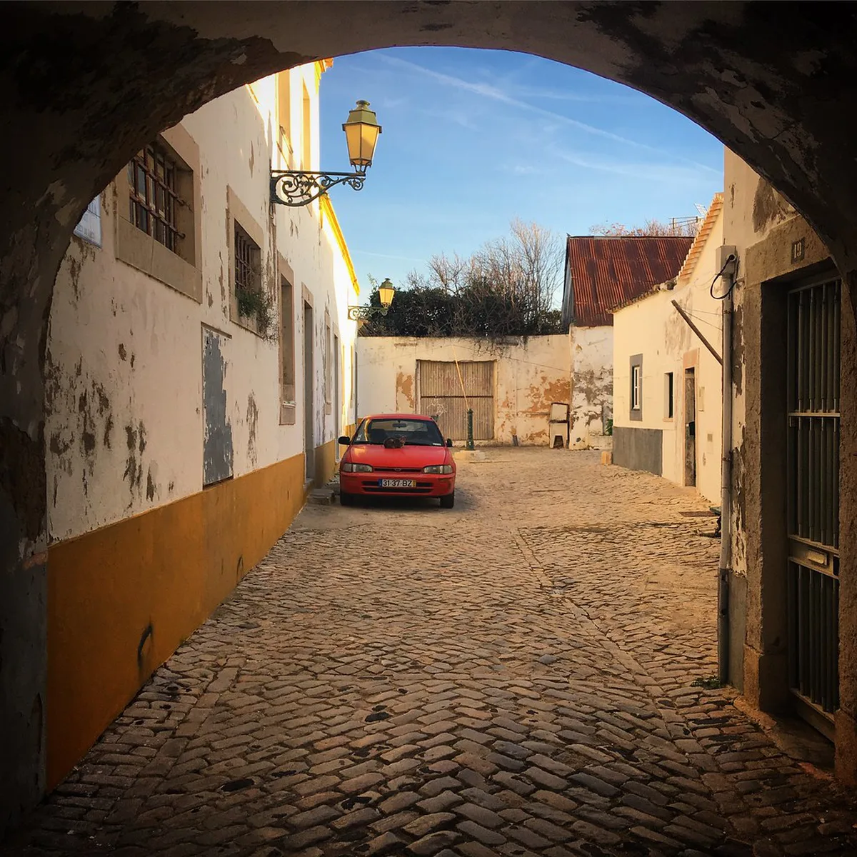 Historic stone arch and old town buildings in Faro, Algarve